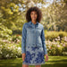 Woman wearing a blue denim jacket over a floral dress on a white background